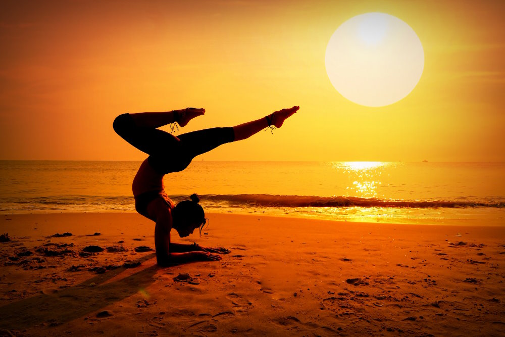 Femme faisant du yoga au coucher de soleil